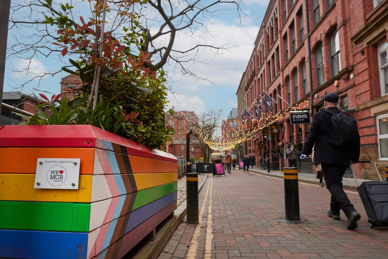 Pedestrians walking along a canal side shopping district in Manchester.